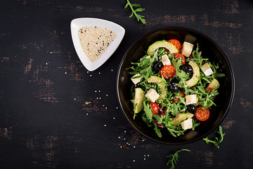 Green salad with sliced avocado, cherry tomatoes, black olives and cheese. Healthy diet vegetarian summer vegetable salad. Table setting. Food concept. Top view.