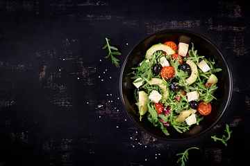 Poster Green salad with sliced avocado, cherry tomatoes, black olives and cheese. Healthy diet vegetarian summer vegetable salad. Table setting. Food concept. Top view. © timolina