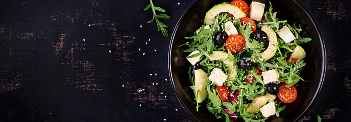 Green salad with sliced avocado, cherry tomatoes, black olives and cheese. Healthy diet vegetarian summer vegetable salad. Table setting. Food concept. Banner. Top view.