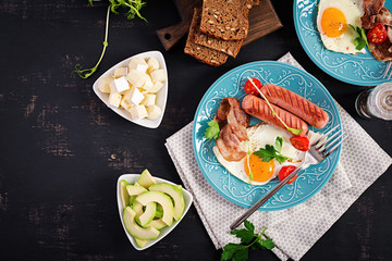 English breakfast - fried egg, tomatoes, sausage and bacon. Top view