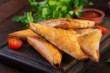 Asian food. Samsa (samosas) with chicken fillet and cheese on wooden background.