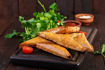 Asian food. Samsa (samosas) with chicken fillet and cheese on wooden background.