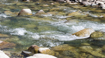 Fototapeta na wymiar Water in the mountain raging river. Beautiful natural background of stones and water. Texture of clear water and fast river. Backdrop with copy space