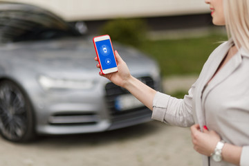 Mockup image of woman holding mobile phone with blank screen. Business woman using phone on car background.