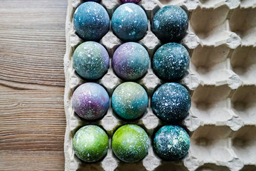 Cooked Easter eggs painted in the style of space and a distant galaxy, against the backdrop of an antique tree. Easter.