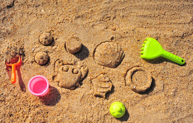 Baby toys on sand beach, top view