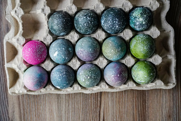 Cooked Easter eggs painted in the style of space and a distant galaxy, against the backdrop of an antique tree. Easter.