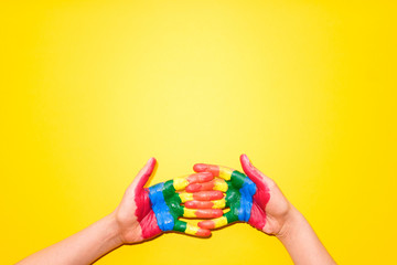 LGBT flag painted on hands on yellow background