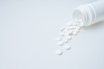 white pills are poured out of plastic packaging on a white background with copy space for text. Opioid epidemic, painkillers and drug abuse concept