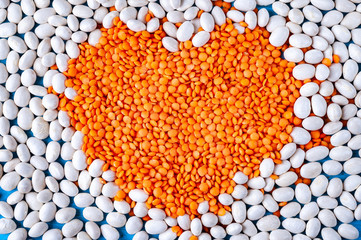 Red lentils in a heart shape on white beans.
