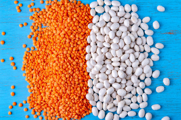 White beans and red lentils on a blue wooden background.