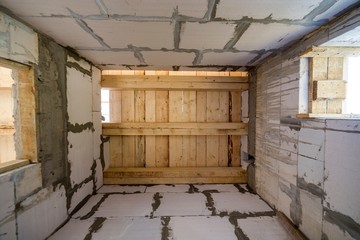 Close-up detail of house room interior under construction and renovation. Energy saving walls of hollow foam insulation blocks, wooden ceiling beams for roof frame.
