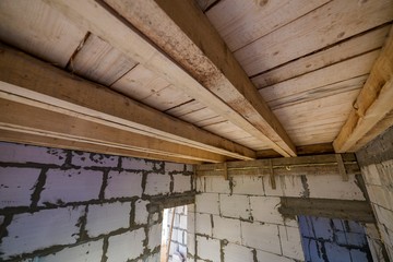 Close-up detail of house room interior under construction and renovation. Energy saving walls of hollow foam insulation blocks, wooden ceiling beams for roof frame.