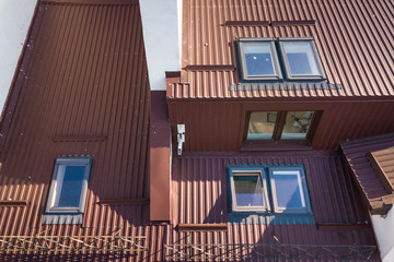 Aerial view of annex room exterior with plastic attic windows, roof and walls covered with brown...