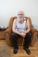Old sick lonely man in the armchair at home