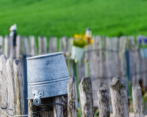 Aluminiowe wiadro na drewnianym ogrodzeniu na wsi. Bawarska wioska. - obrazy, fototapety, plakaty