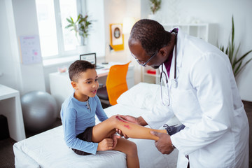 Obraz premium Pediatrician looking at leg of boy after falling from bike