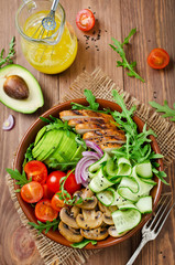 Healthy salad bowl with chicken, mushrooms, tomatoes, cucumbers, avocado and arugula
