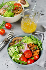 Healthy salad bowl with chicken, mushrooms, tomatoes, cucumbers, avocado and arugula
