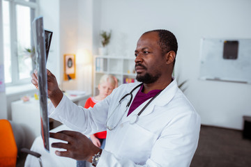 Fototapeta premium Dark-eyed doctor feeling concerned while checking x-ray of girl