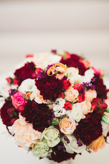 Beautiful toned picture with wedding rings against the background of a bouquet of flowers