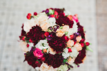 Beautiful toned picture with wedding rings against the background of a bouquet of flowers
