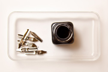 ink bottle with metal tips for ink pen on a white background. stationery on white desk close up top...