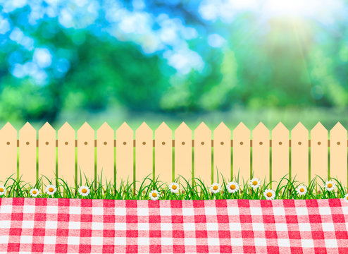 a picnic outdoor, tablecloth in backyard and wooden garden fence