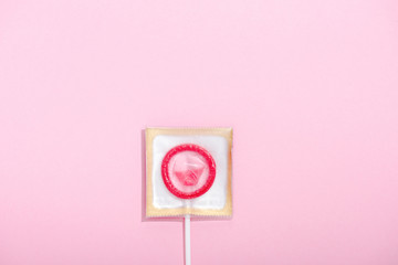 top view of condom wrapped as lollipop on pink with copy space, Safe Sex concept