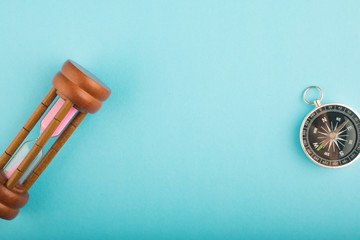 hourglass and compass on blue background for direction or running out of time concept, copy space for text