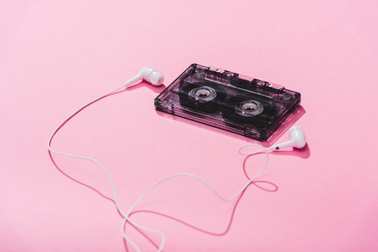 vintage audio cassette with earphones on pink, music concept