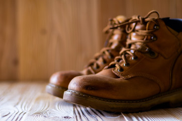 Yellow leather used work boots on wooden background closeup. Place for text