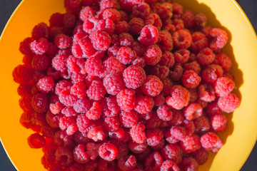 a lot of raspberries on the yellow plate