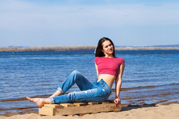Fototapeta na wymiar Portrait of a young beautiful woman in trendy jeans posing against the backdrop of the Volga River