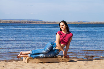 Portrait of a young beautiful woman in trendy jeans posing against the backdrop of the Volga River