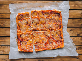 Homemade pizza rectangle form with cheese and salami lies on papyrus on the background of a brown...