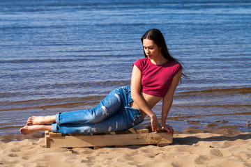 Portrait of a young beautiful woman in trendy jeans posing against the backdrop of the Volga River