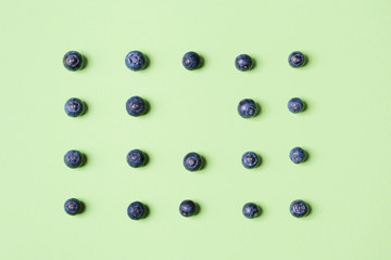 Pattern of fresh blueberries in on pastel green background. Healthy breakfast concept