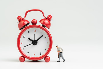 Working hours, time to go to work or meeting schedule concept, miniature figure businessman with suit and suitcase walking with big red alarm clock on white background with copy space