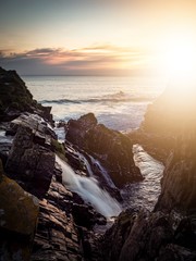 Obraz premium Sunset over a coastal waterfall