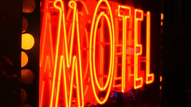 Flashing lights illuminate a neon motel sign