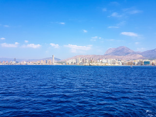 Fototapeta na wymiar Beautiful Levante beach in Benidorm, Spain. Image taken from the sea, with the skyline of skyscrapers and a boat of first motive. Concept of holidays in Benidorm.