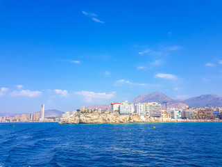 Fototapeta premium Beautiful Levante beach in Benidorm, Spain. Image taken from the sea, with the skyline of skyscrapers and a boat of first motive. Concept of holidays in Benidorm.