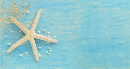 Fototapeta na wymiar Seastar and white pearls on blue wooden background