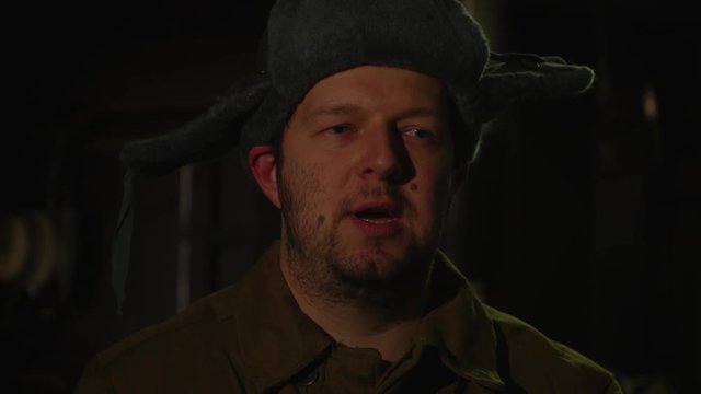 Russian man in a hat with earflaps, talking on the phone in a dark basement and decides matters of national importance.
