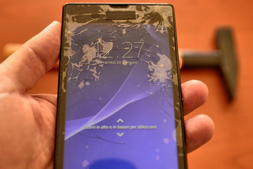 Close up on a smartphone screen with a broken screen and a thousand cracks