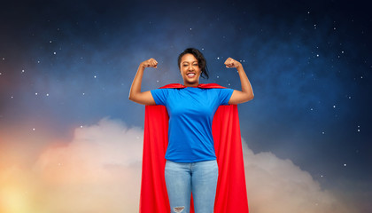super power and people concept - happy african american young woman in superhero red cape over starry night sky and clouds background