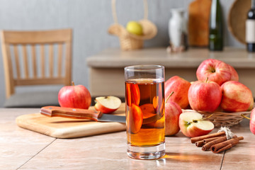 Glass of apple juice and ripe pink apples on a kitchen table