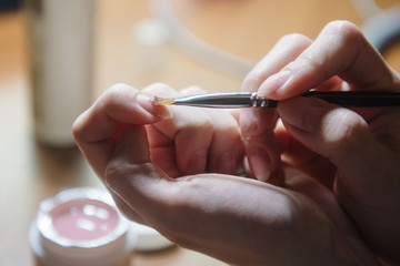 Manicurist applies varnish on the nail close up