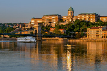 Naklejka premium View at the Royal Castle of Budapest and the Szechenyi Chain Bridge. Center of Budapest and the River Dunayyat in the morning. In foreground pleasure boat. Hungary. European travel.
